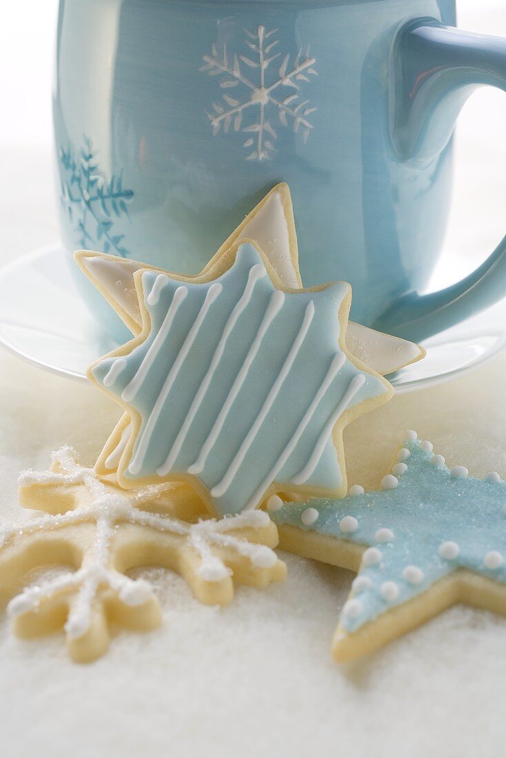 Iced Christmas biscuits in front of blue cup