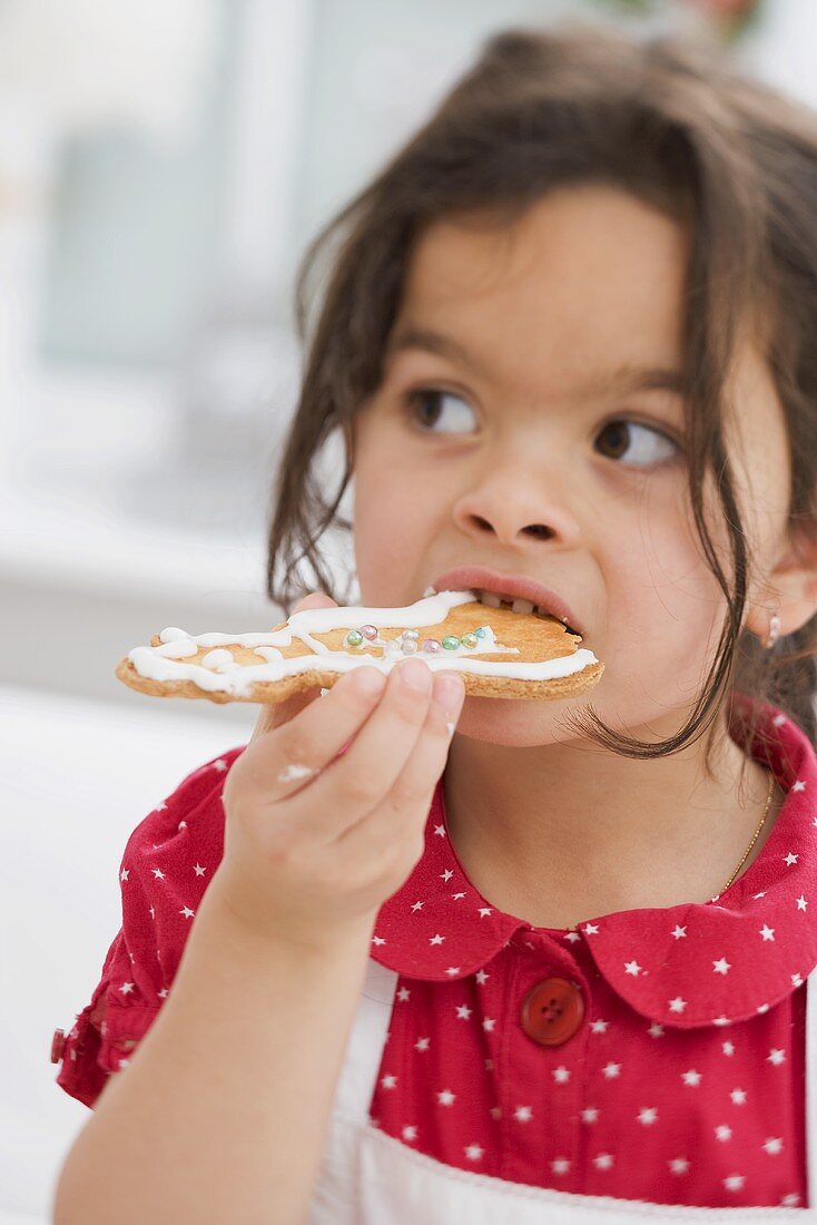 Kleines Mädchen isst selbst gebackenes Weihnachtsplätzchen