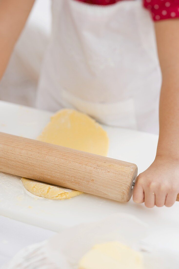 Kleines Mädchen rollt Teig aus