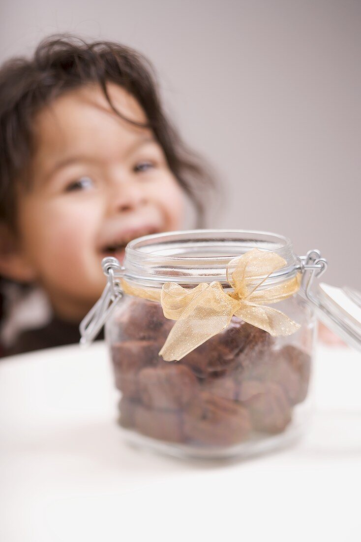 Chocolate biscuits in storage jar, child in background