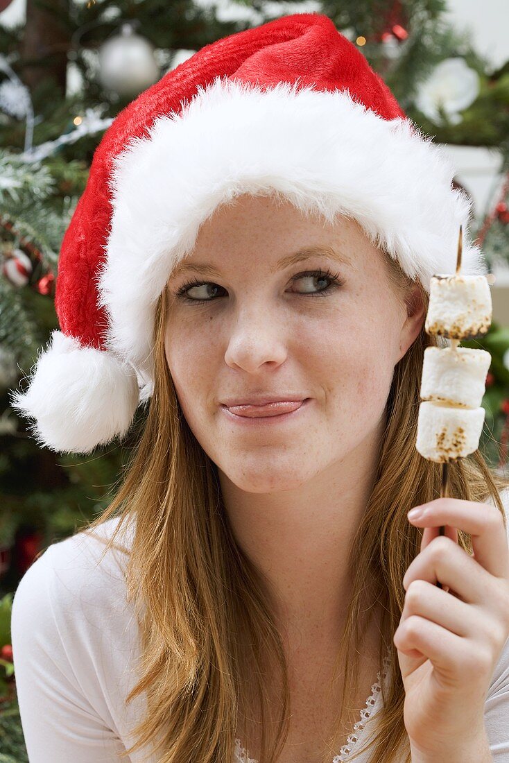 Frau mit Nikolausmütze hält Marshmallow-Spiess