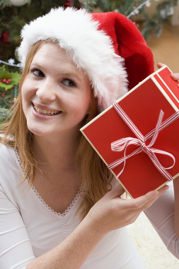 Frau mit Nikolausmütze hält Weihnachtsgeschenk
