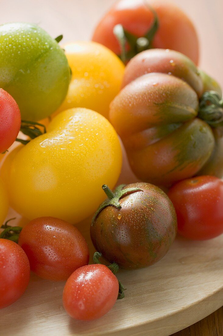 Various types of tomatoes on wooden plate (detail)