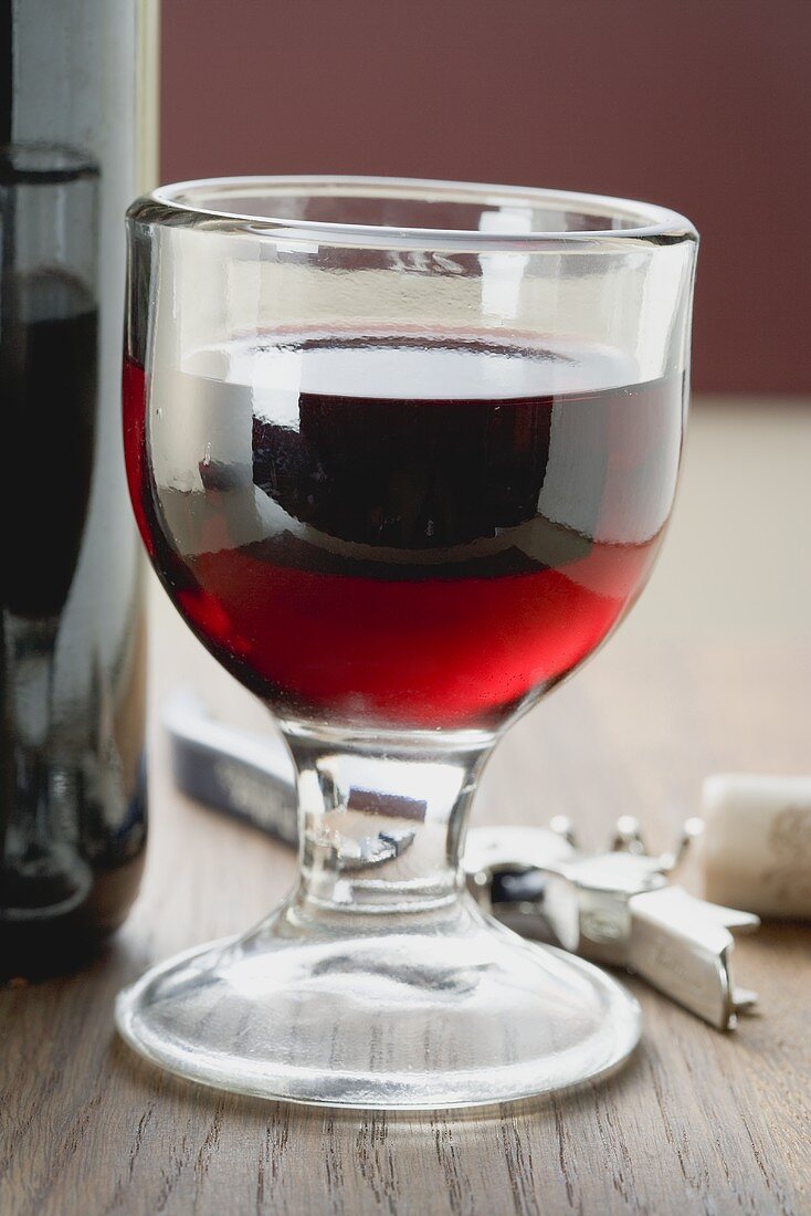 Rotweinglas zwischen Flasche und Korkenzieher