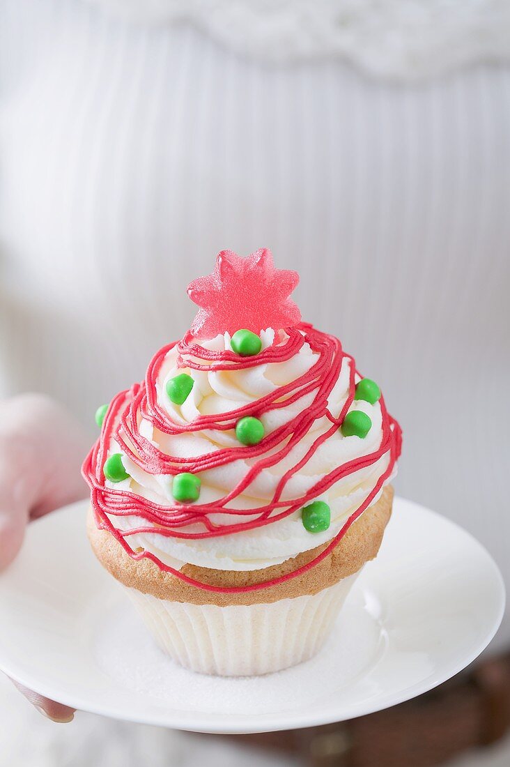 Frau hält Cupcake auf Teller (weihnachtlich)