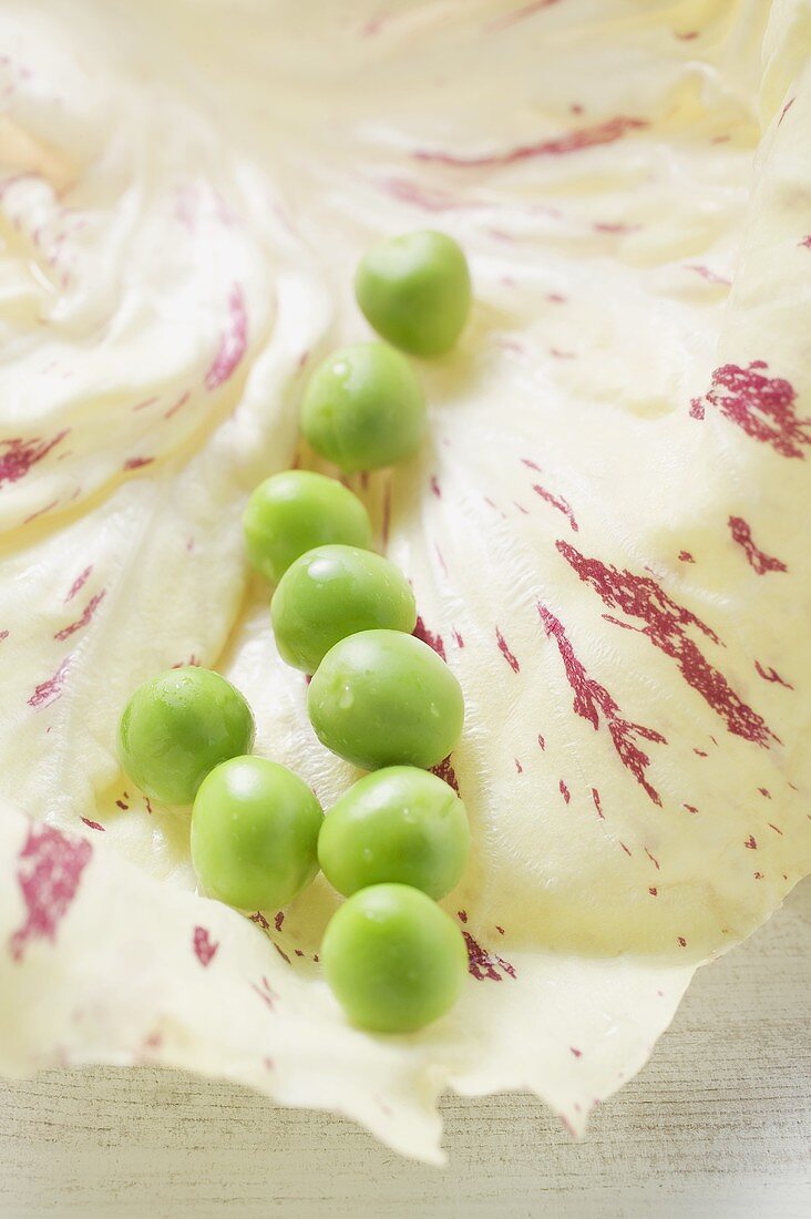 Several peas on radicchio leaf