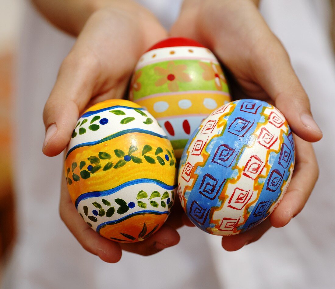 Child's hands holding three Easter eggs