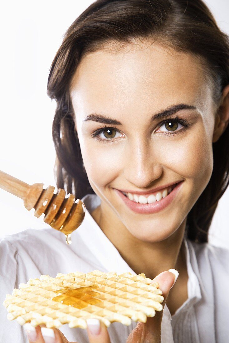 Young woman eating waffle with honey