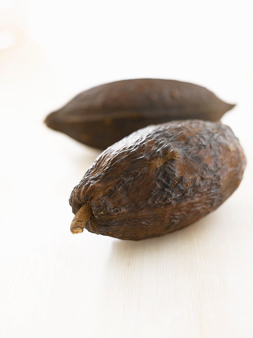 Zwei Kakaofrüchte auf weisser Holzplatte