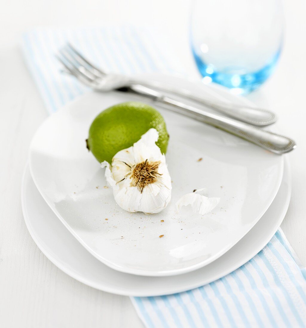 Lime and garlic with knife and fork on white plate
