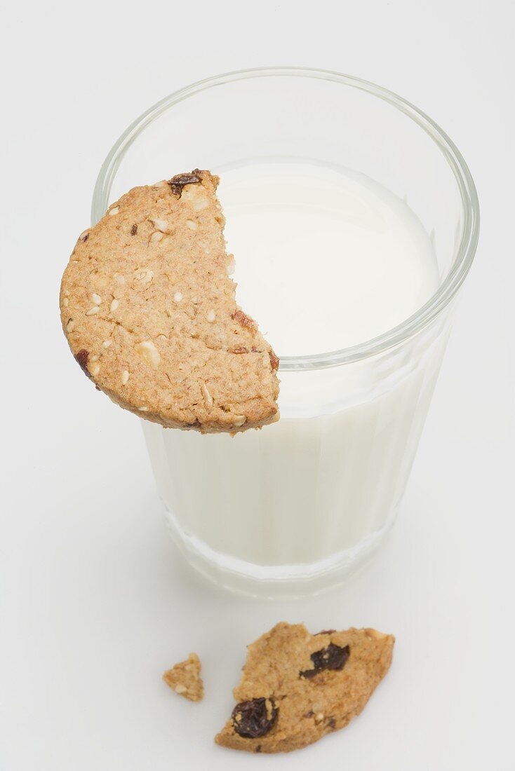 A glass of milk with a piece of wholemeal biscuit