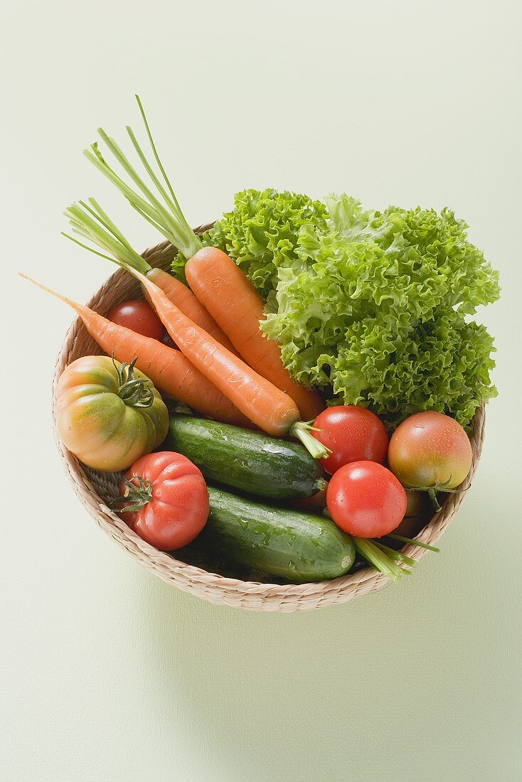 Fresh tomatoes, cucumbers, carrots & lettuce in small basket