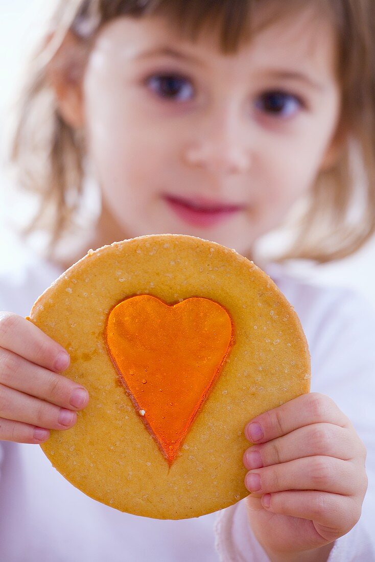 Small girl with window cookie (biscuit with sugar window)