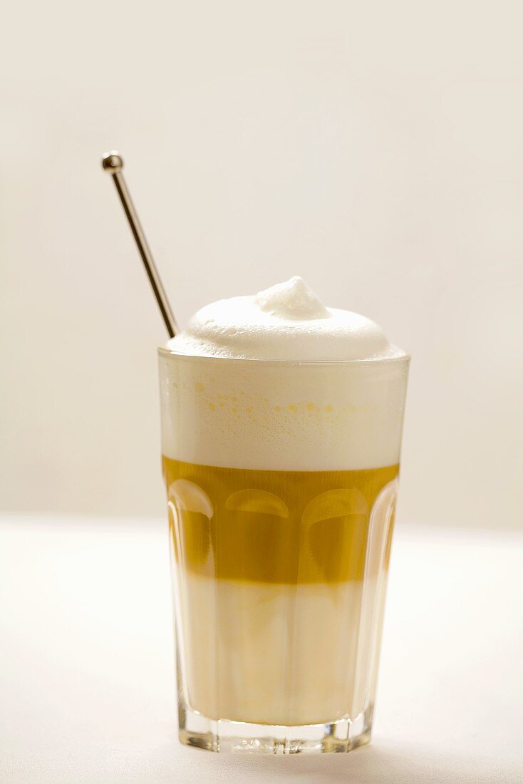 Ein Glas Latte Macchiato mit Kaffeelöffel