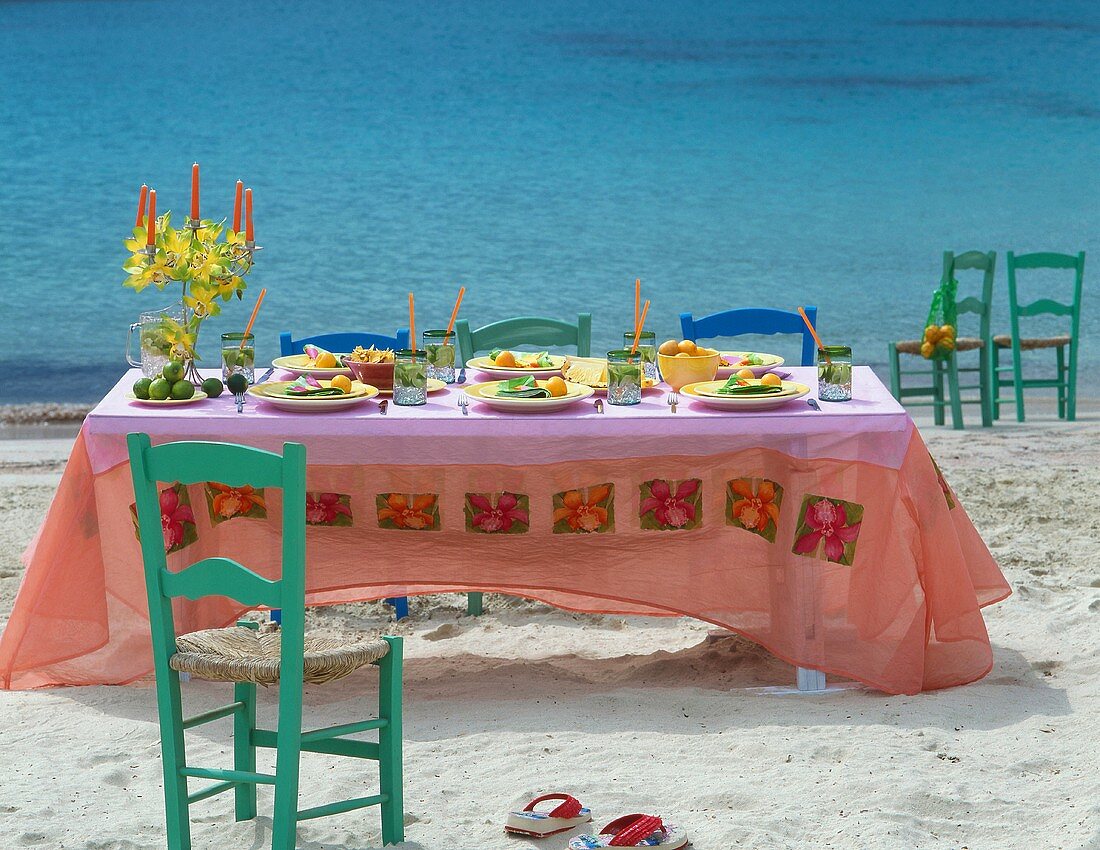 A table on the beach laid with fruit and drinks