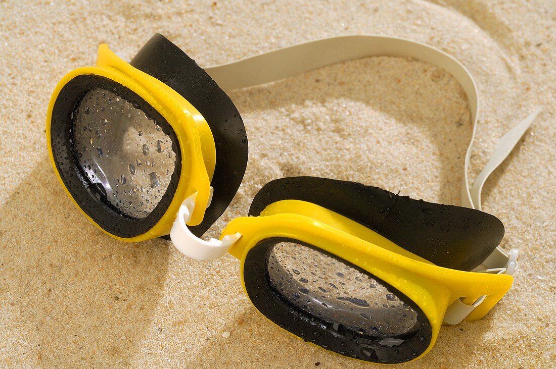 Gelbe Schwimmbrille im Sand