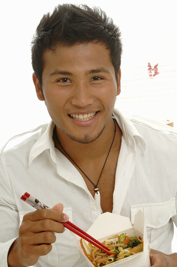 Mann isst asiatisches Gericht mit Garnelen aus der Lunchbox