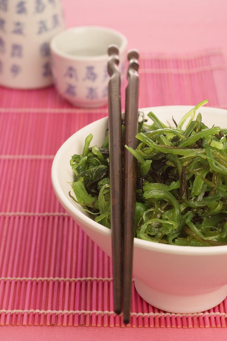 Seaweed salad with chopsticks, sake cup in background