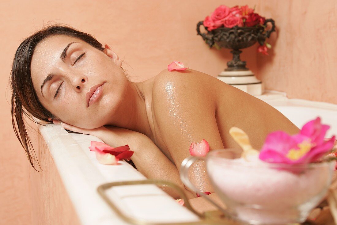 Junge Frau in der Badewanne mit Blütenblättern