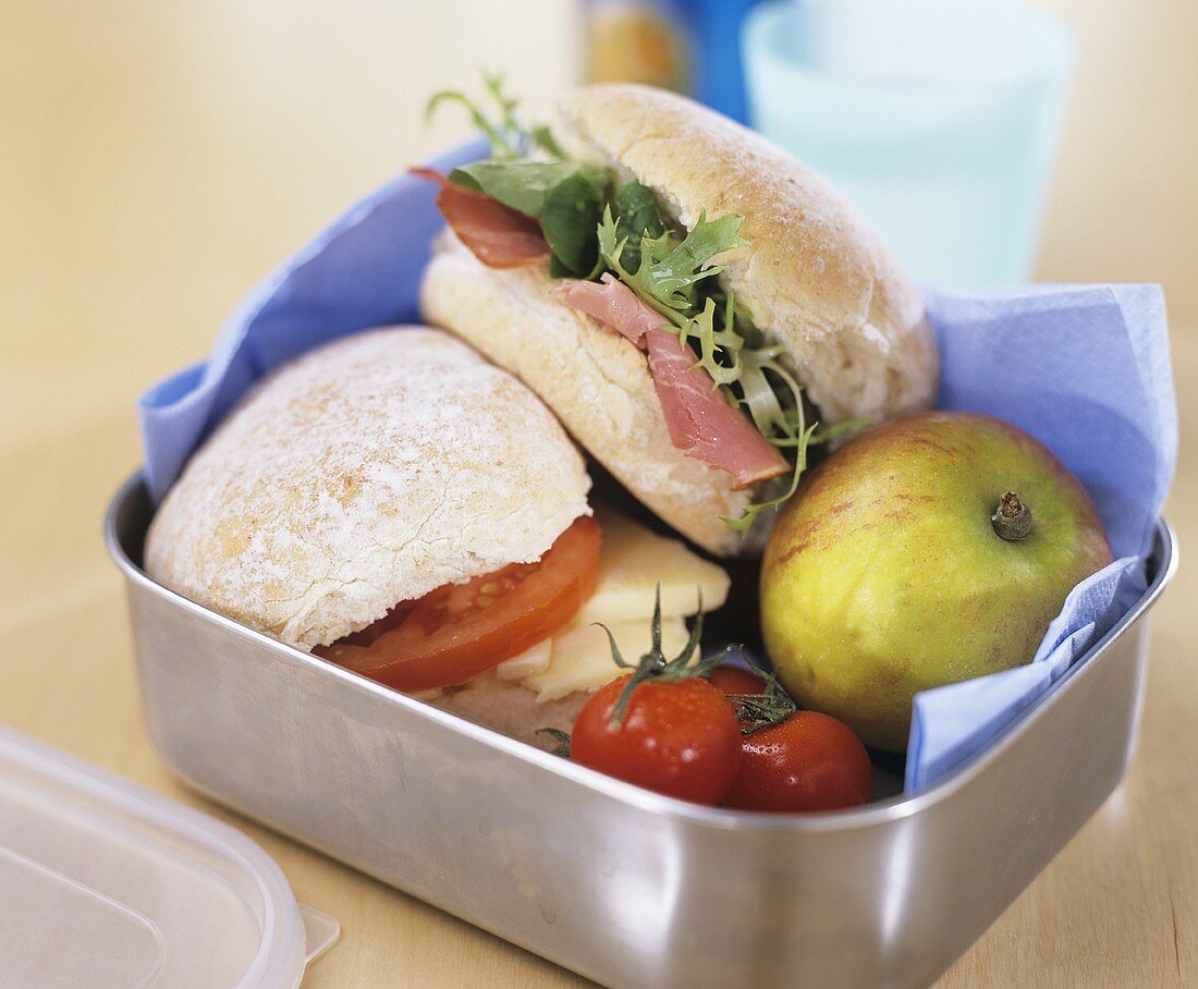 Two sandwiches, apple and tomatoes in a lunch box