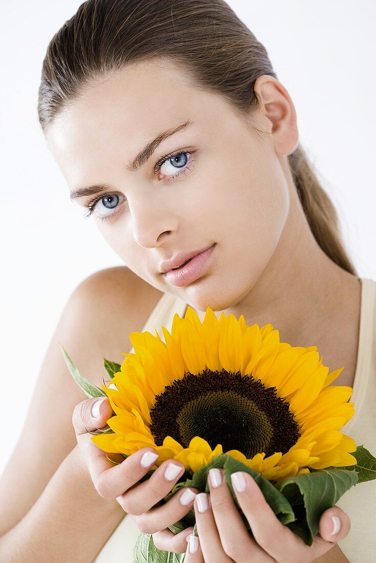 Junge Frau hält eine Sonnenblume in der Hand