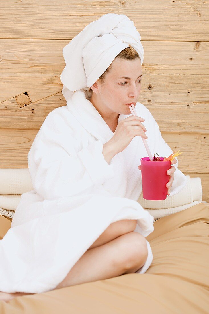 Woman in bathrobe drinking fruit cocktail