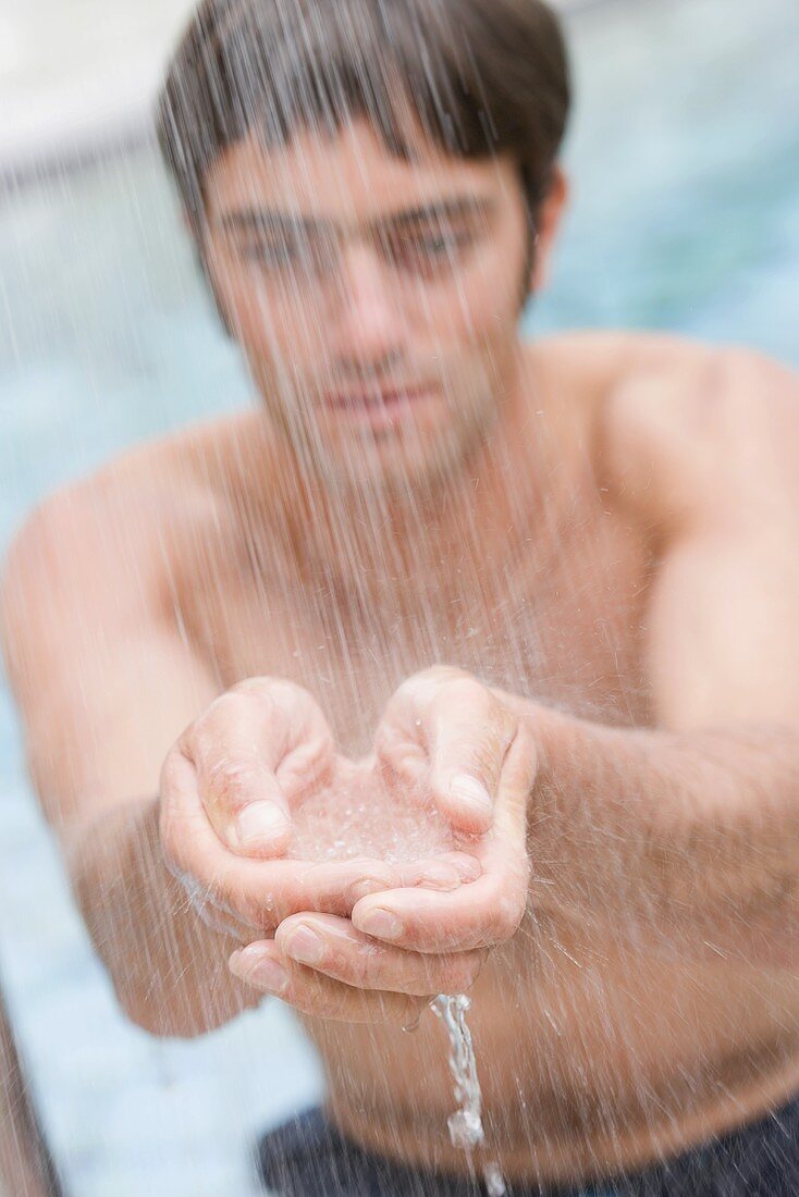 Junger Mann steht unter der Dusche