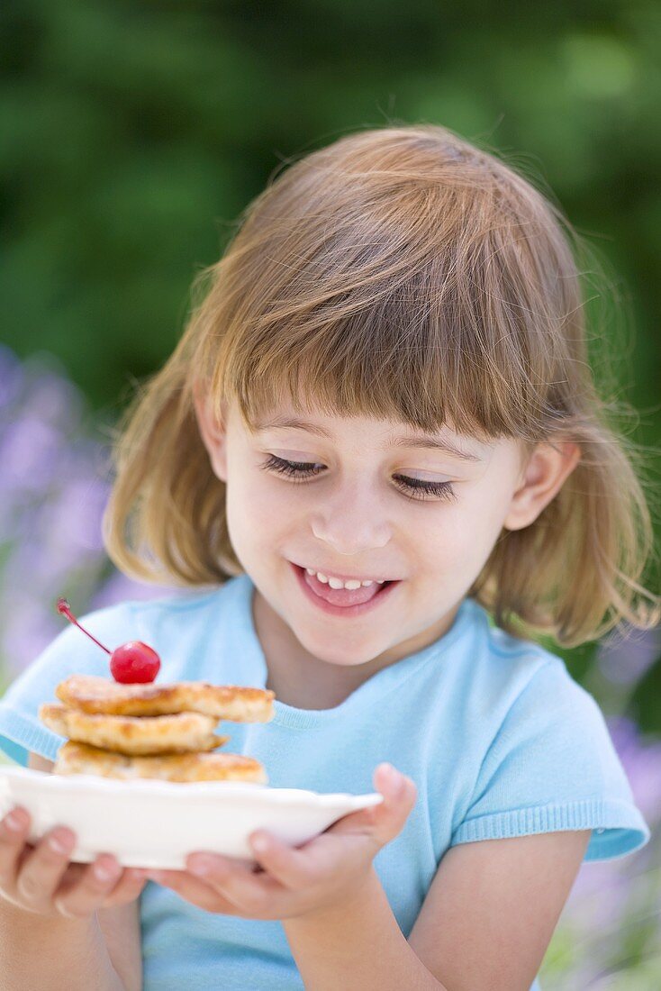 Little girl holding plate of apple pancakes