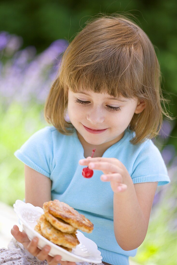 Kleines Mädchen hält Teller mit Apfel-Pancakes