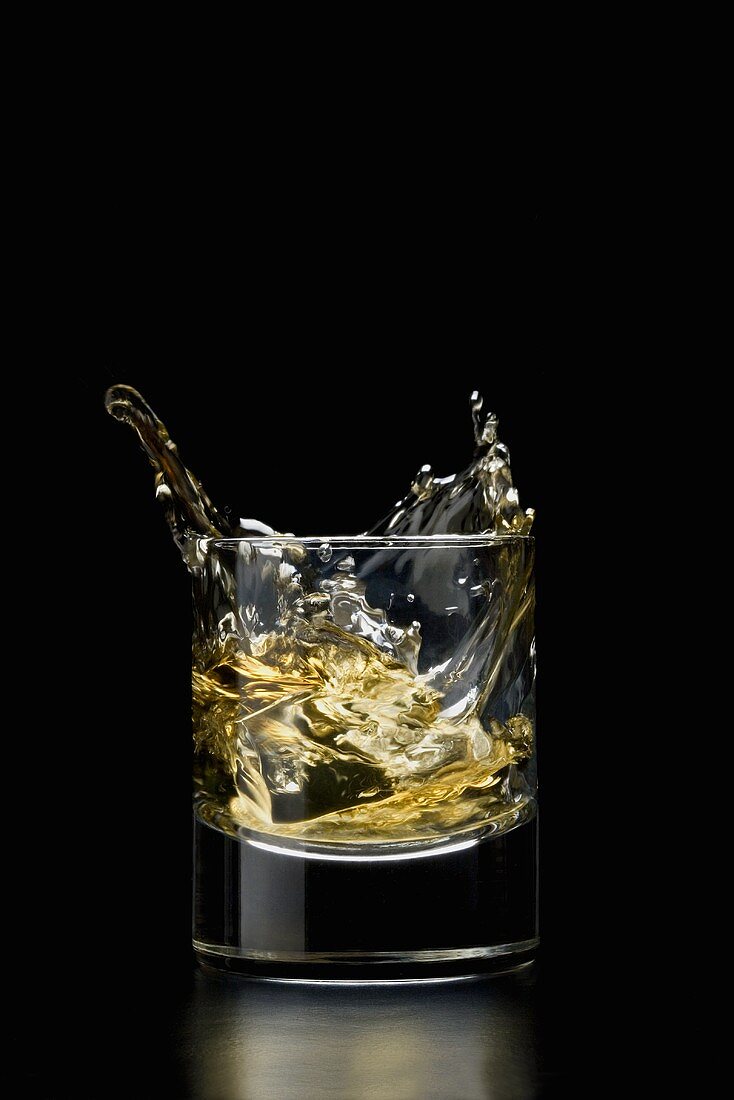 Eiswürfel fällt in ein Whiskyglas