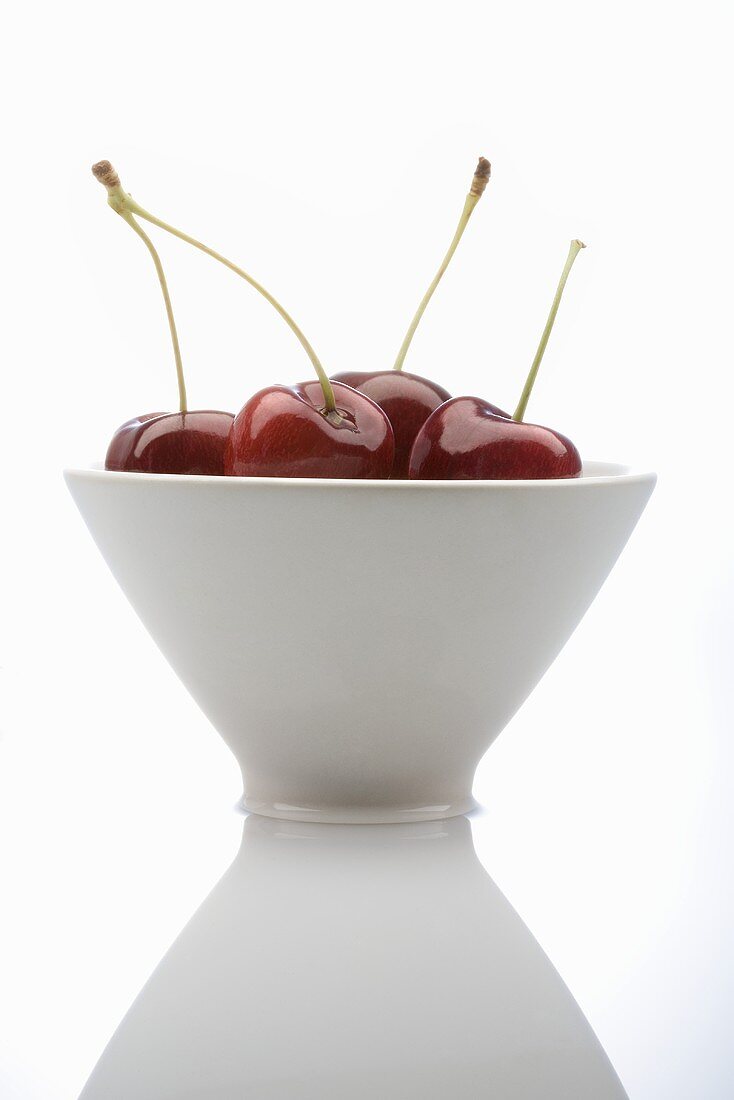 Four cherries in a white bowl