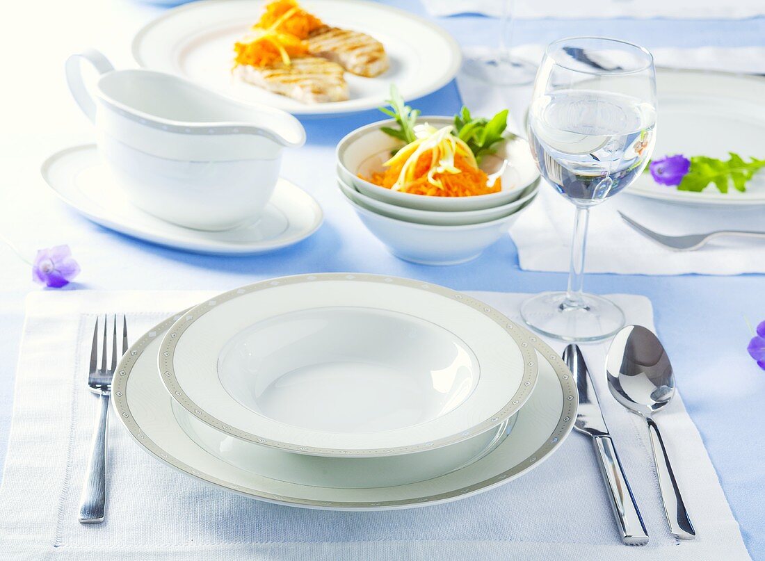 Gedeck mit weißem Teller, Wasserglas und Salat
