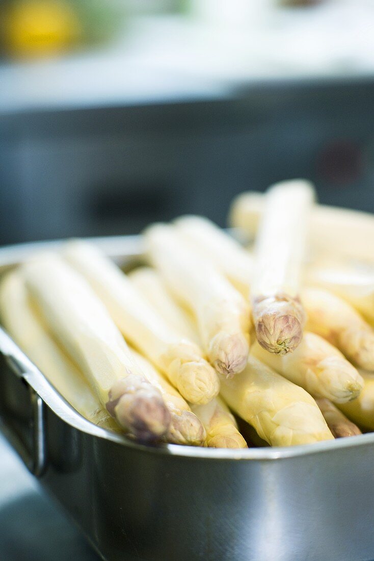 Peeled white asparagus spears in a roasting tin