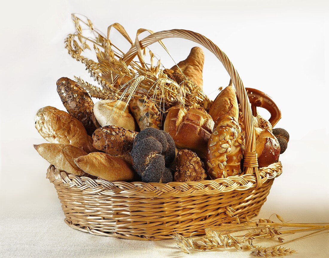 Verschiedene Brötchen, Brote und Getreideähren im Brotkorb