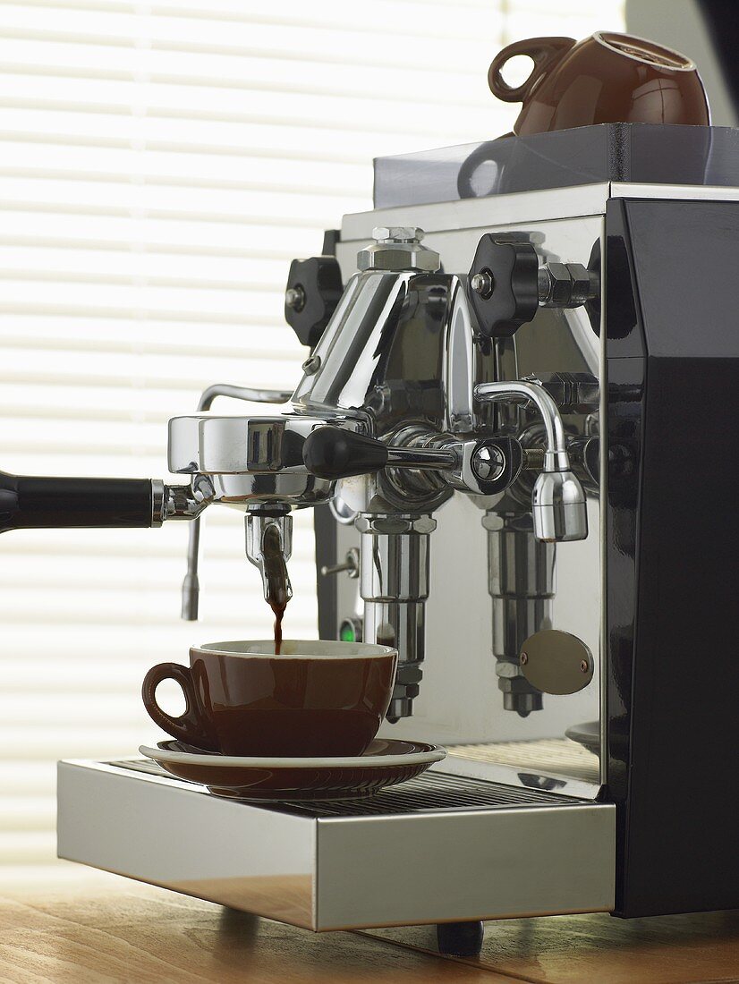 Espresso läuft aus verchromter Espressomaschine in eine Tasse