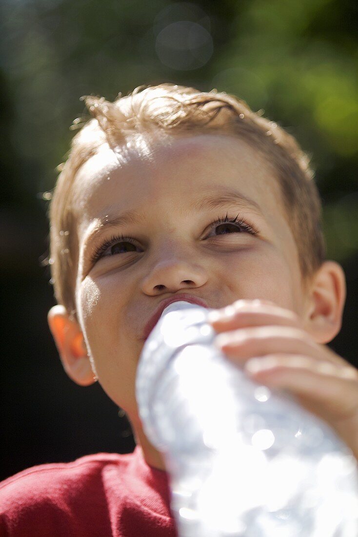 Boy drinking mineral water out of a bottle