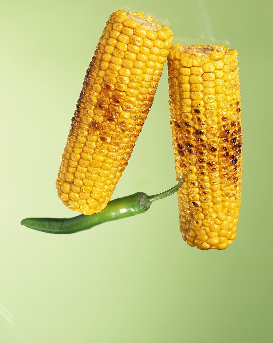 Grilled corn cobs and a green chilli pepper