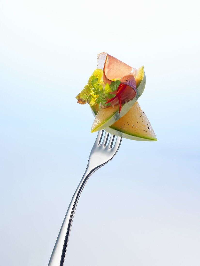 Melon, lettuce and ham on a fork