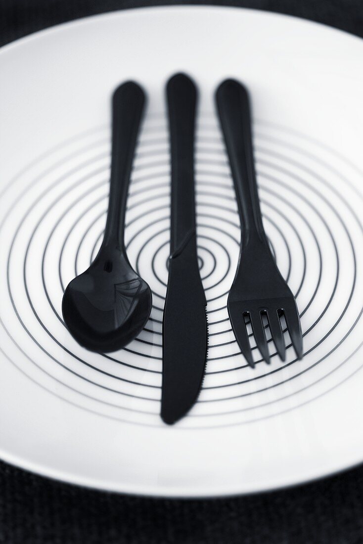 Black plastic cutlery on a plate