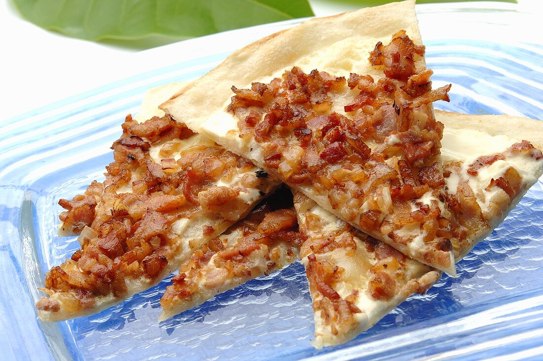 Pieces of tarte flambée with onion and bacon topping
