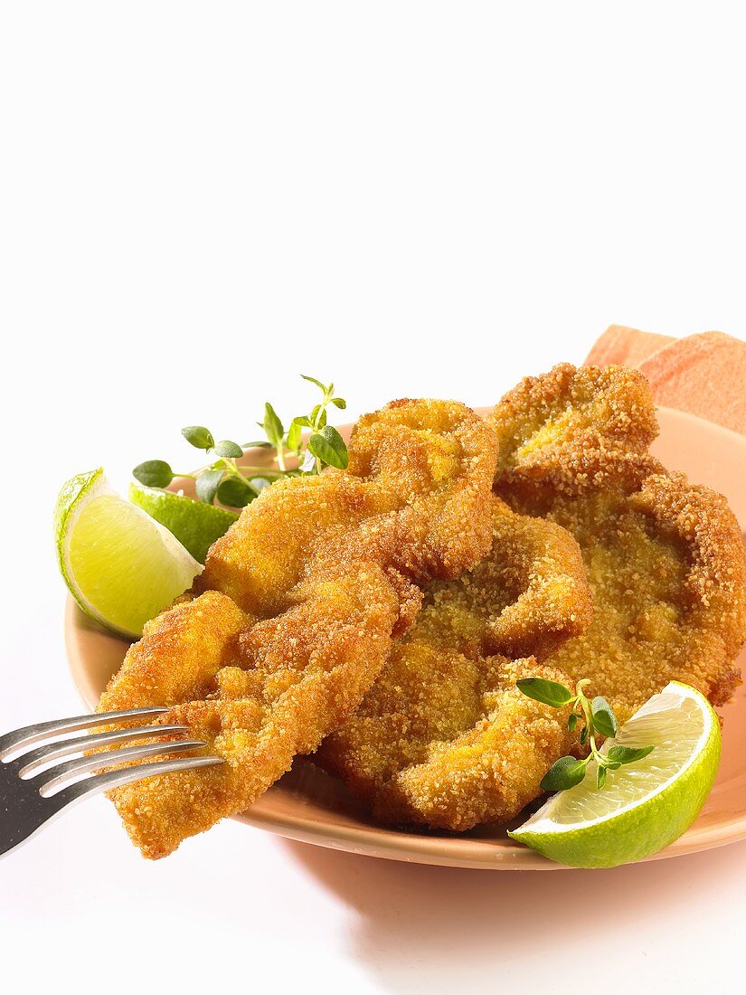 Breaded escalopes with lime wedges