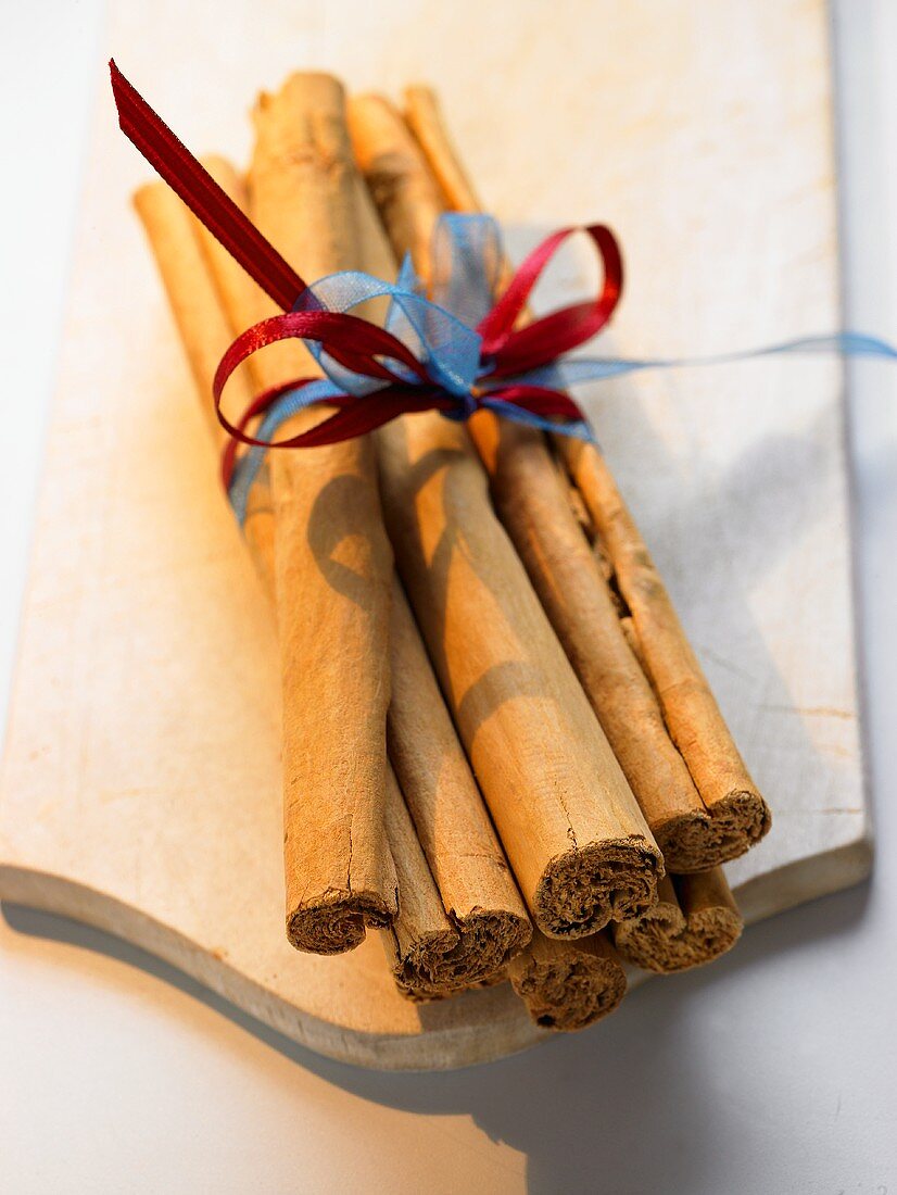 A bundle of cinnamon sticks on chopping board