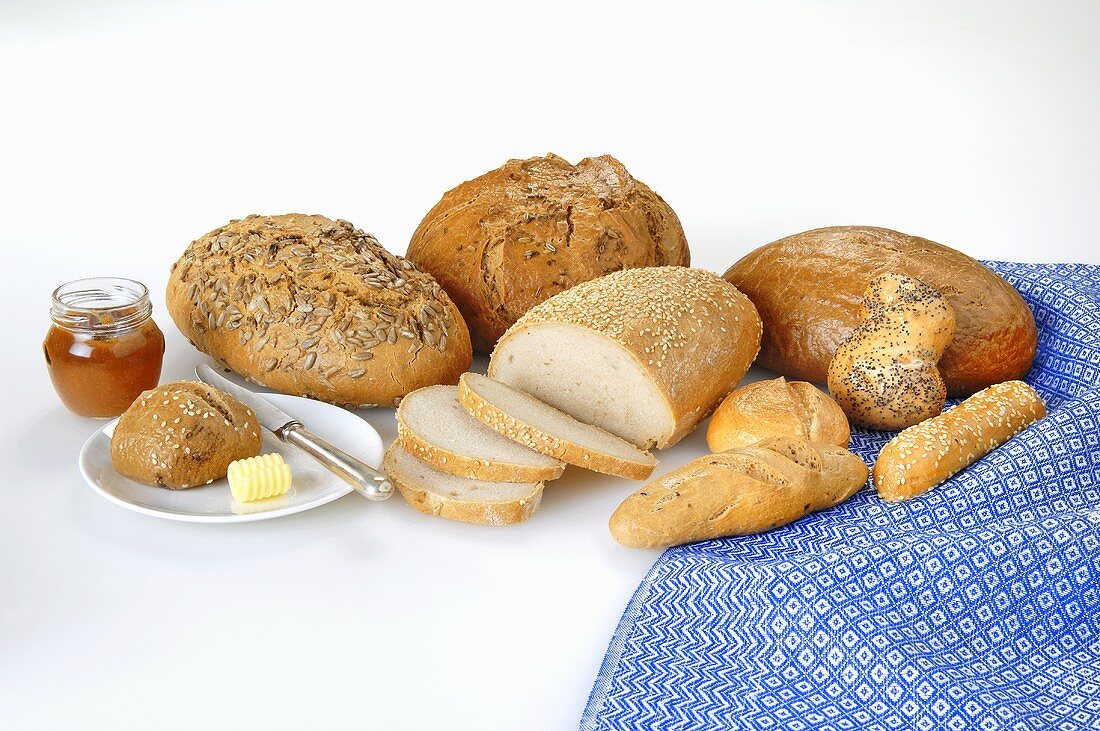 A variety of breads and rolls with butter and marmalade