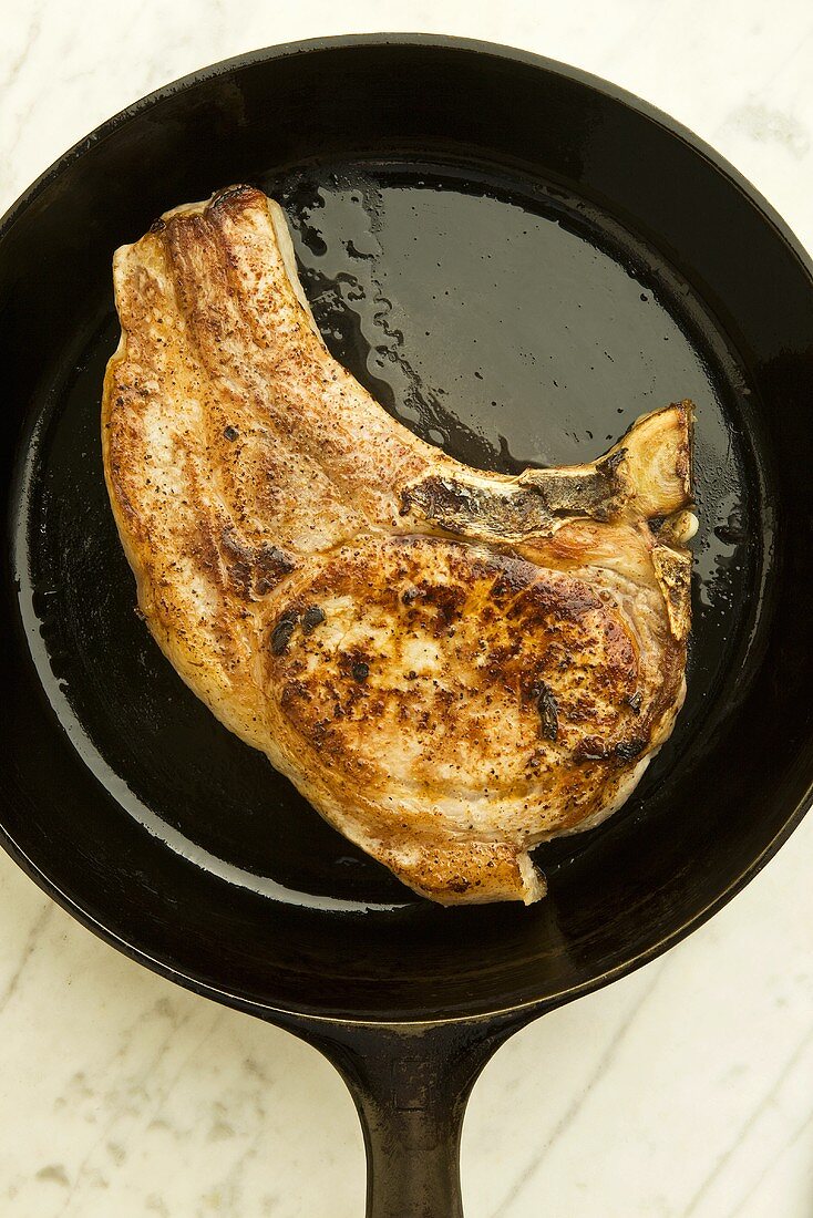 Fried pork chop in frying pan from above