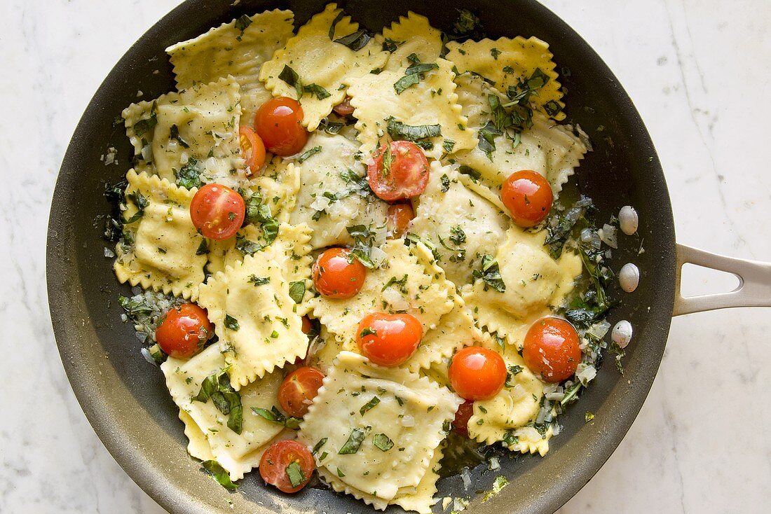 Ravioli mit Tomaten und Basilikum in Pfanne