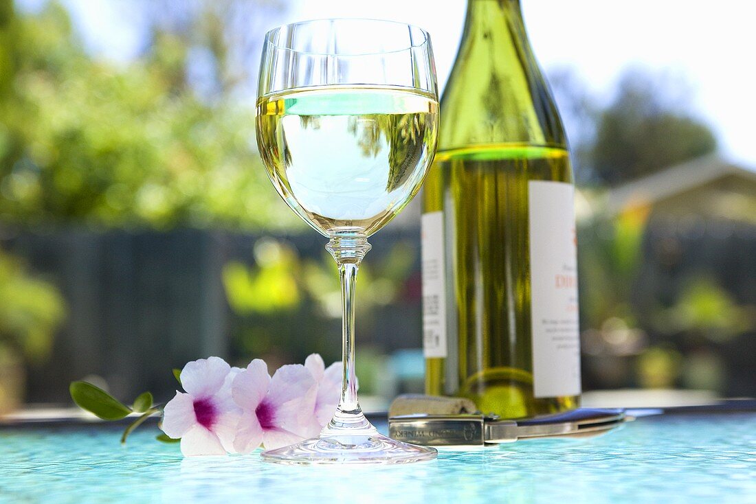 Glass and Bottle of White Wine on an Outdoor Table; Poolside