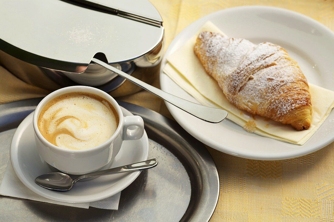Caffe crema, a croissant and a sugar tin