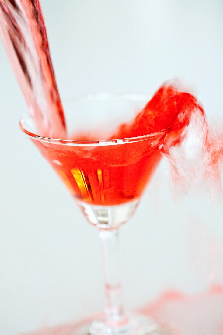 Red Martini being poured into a glass