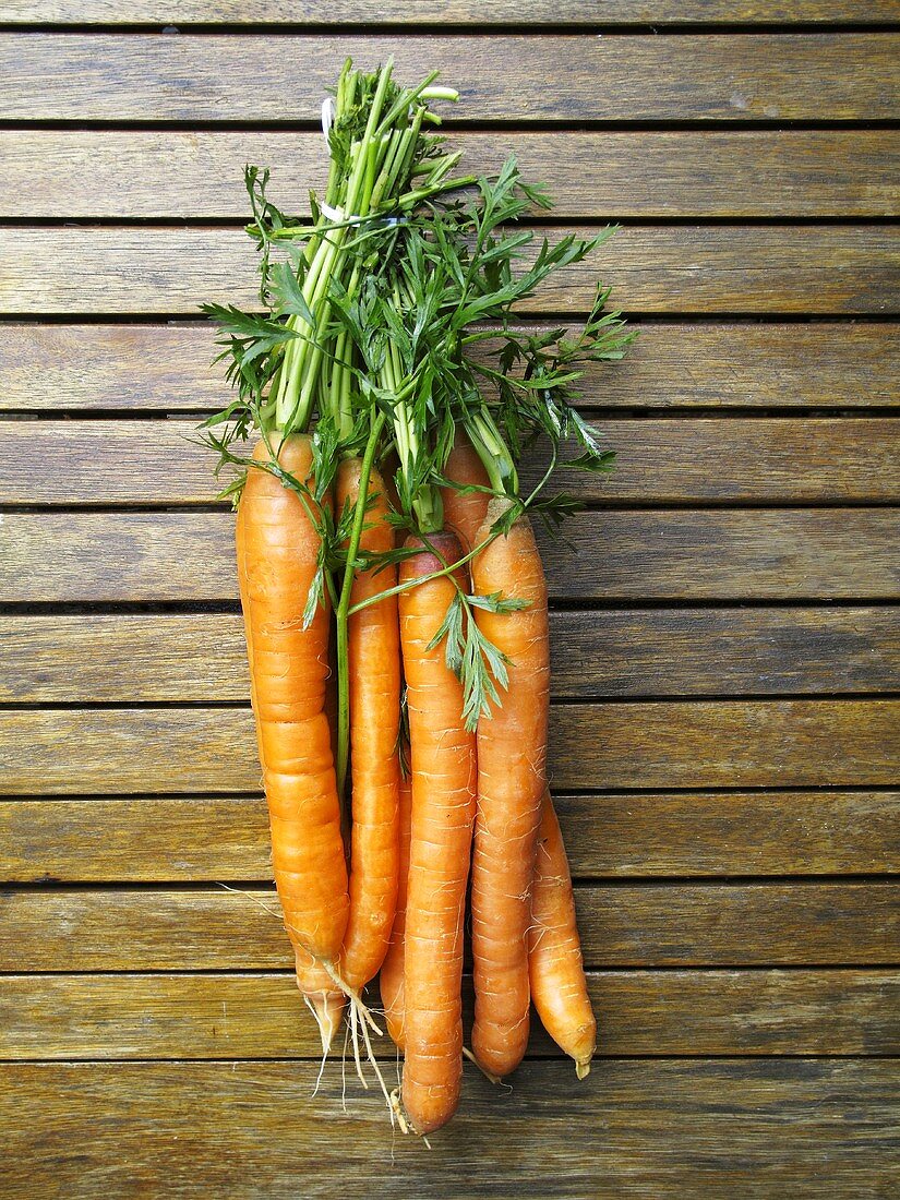 Fresh carrots on a wooden surface, seen from above