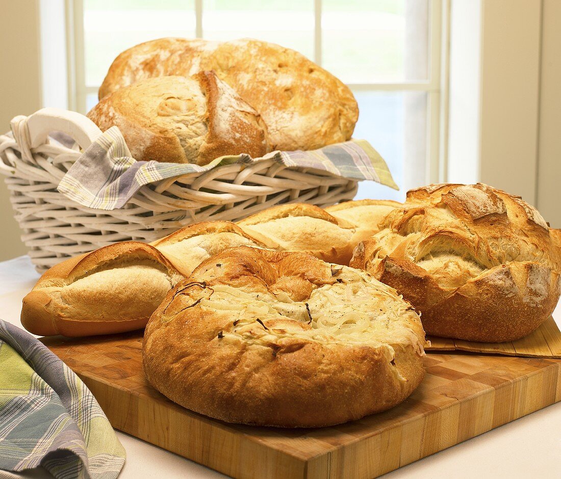 Verschiedene Brote auf Schneidebrett und im Brotkorb